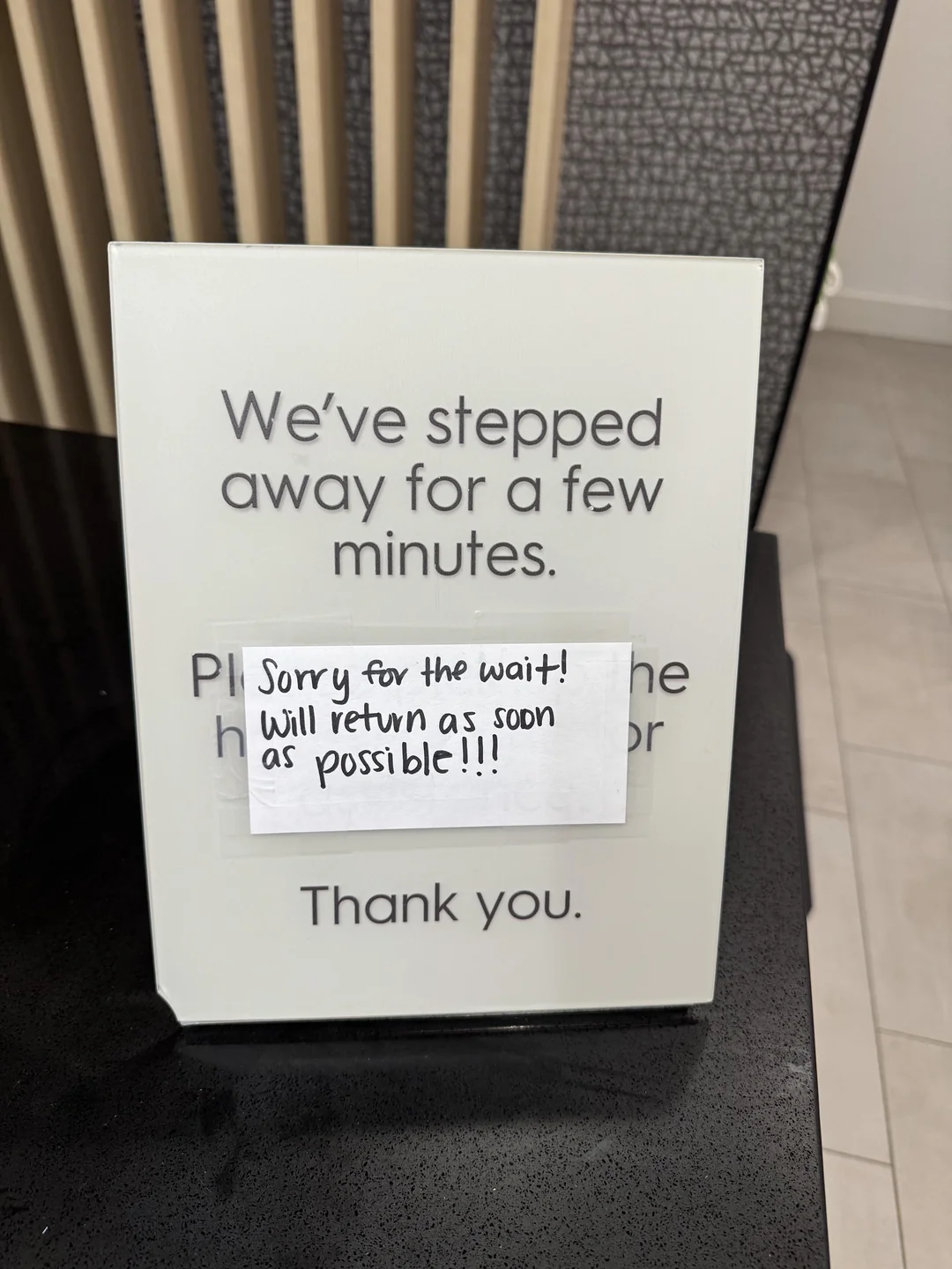 Empty hotel front desk with a printed 'back in a few minutes' placard